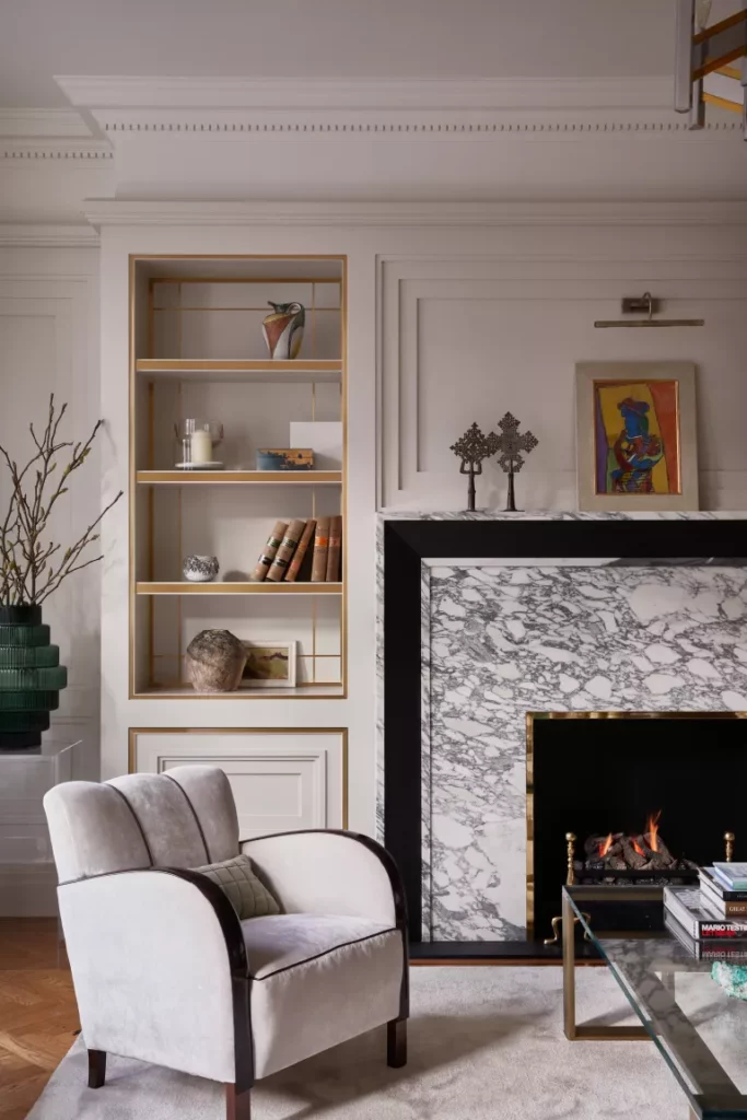 salon neutre avec sol en bois, cheminée en marbre, fauteuil, alcôve