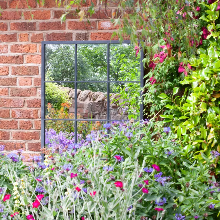 mur de briques avec fenêtre style miroir de jardin avec plantes devant