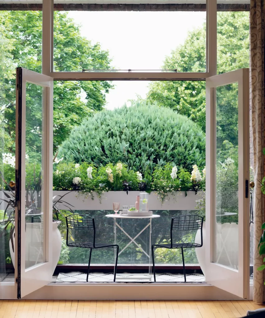 Exemple d'idées de jardin sur balcon avec une petite table bistro et des chaises donnant sur des jardinières.