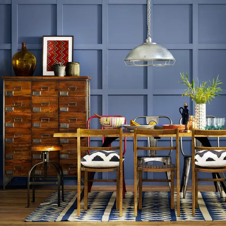 Salle à manger bleue avec des panneaux muraux, des meubles en bois et un tapis à motifs.