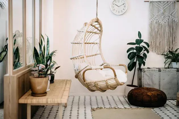 Chaise suspendue confortable dans le salon du loft avec un design élégant et bohème. Bien conçu et décoré avec un assortiment de plantes intéressantes.
