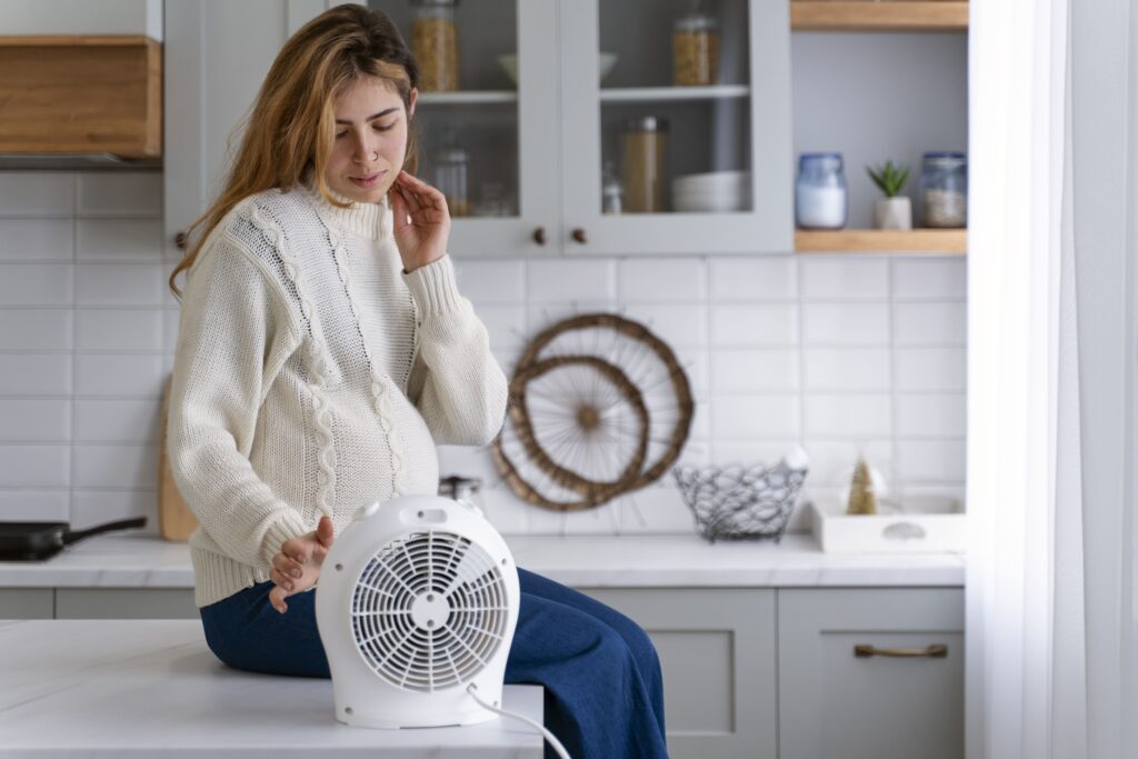femme assise sur le plan de travail avec un ventilateur portable chaud été comment se rafraichir avec un ventilateur astuce