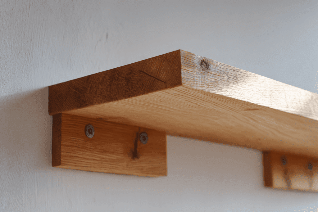 Détail d’une étagère en bois brut fixée avec équerres métalliques noires, vis apparentes, mur en briques ou béton ciré, ambiance industrielle. Mise en valeur de la solidité, outils de bricolage à proximité, photo réaliste haute définition.